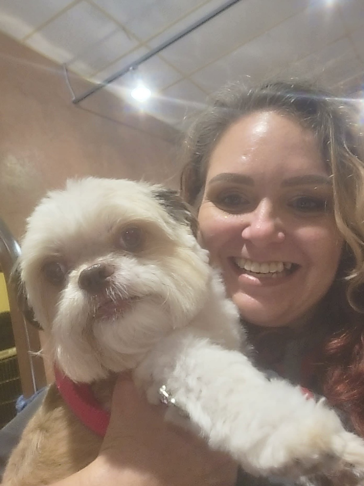 Erica smiling with a freshly groomed fluffy white dog